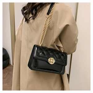 Close-up of black quilted shoulder bag with gold chain strap and ornate metal buckle