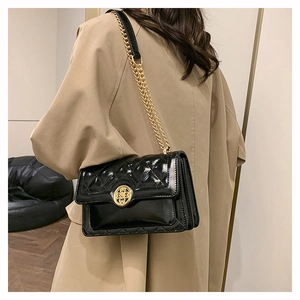 Close-up of quilted black crossbody bag with gold floral clasp and chain strap