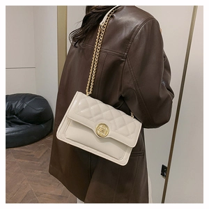 Quilted chain shoulder bag in beige with gold circular hardware on a leather texture