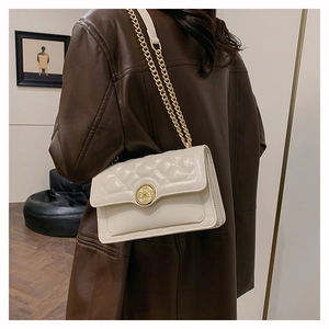 Detail of elegant beige quilted shoulder bag with gold chain and circular clasp