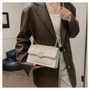 Close-up of cream quilted chain bag with gold metal hardware and ornate circle clasp