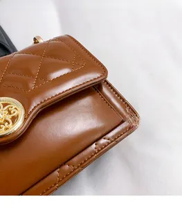 Detail of quilted brown leather bag with an ornate golden floral engraved lock
