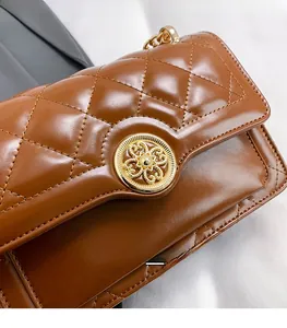 Detail of caramel quilted leather texture and vintage gold round rotating lock