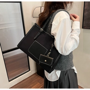 Détail du sac cabas noir avec coutures contrastées blanches et mini pochette assortie