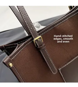 Detail of deep brown tote bag featuring white contrast stitching and gold metal hardware