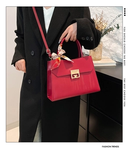 Detail of red leather handbag with silk scarf handle and elegant gold square metal buckle