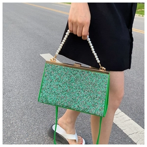 Close-up of green sequin evening bag with faux pearl handle and gold metal clasp
