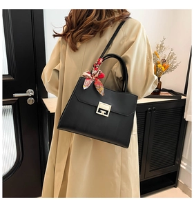 Detail of black leather tote bag featuring G-shaped gold buckle and silk scarf handle