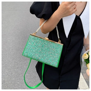 Detail of green sequin handbag with pearl handle and detachable shoulder strap on model