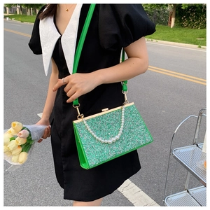 Close-up of emerald green sequin crossbody bag with pearl handle and golden hardware