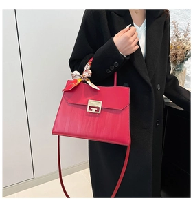 Detail of red leather crossbody bag with metal buckle and polka dot scarf accessory