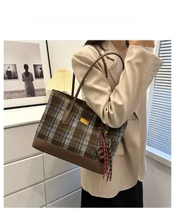 Détail du sac cabas en laine à carreaux avec base en cuir brun et bijou de sac