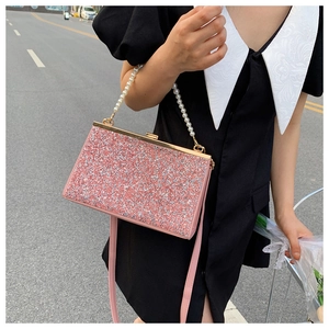 Close-up of pink sequined evening bag with pearl handle and golden metallic clasp