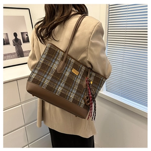 Vue détaillée du sac cabas à carreaux marron avec lanières en cuir et pompon sur modèle