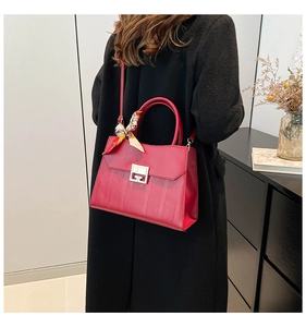 Detail of red tote bag with silver rotary buckle and decorative silk scarf on handle