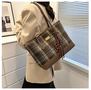 Détail du grand sac cabas en laine à carreaux avec poignées en cuir sur l'épaule