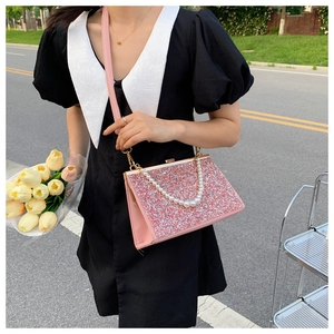 Detailed view of a pink glitter handbag featuring elegant pearl handles and a PU strap