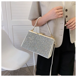 Detail of silver glitter clutch bag with pearl handle and golden frame closure