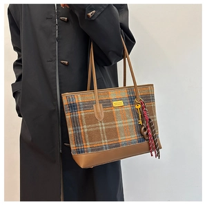 Gros plan du sac cabas à carreaux vintage avec détails en cuir brun et porte-clés métal