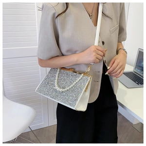 Detail of white sequin evening bag featuring a pearl handle and metal frame closure