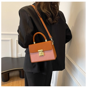 Detail of color-block box bag with pink pleats and orange leather handle on model