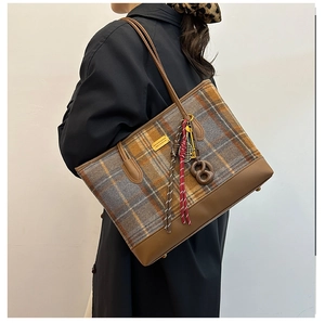 Détail du grand sac cabas en laine à carreaux avec lanières en cuir et breloques