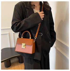 Detail of caramel and pink paneled handbag featuring a golden metallic twist lock closure