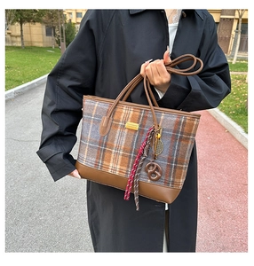 Détail d'un grand cabas en laine à carreaux avec lanières en cuir et breloques