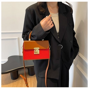 Detail of red pleated fabric and brown leather flap contrast on the box handbag