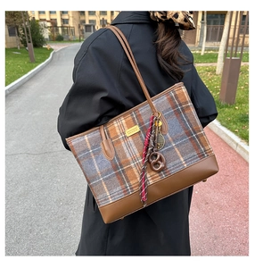 Détail du sac cabas à carreaux en laine avec des pendentifs créatifs et des finitions en cuir