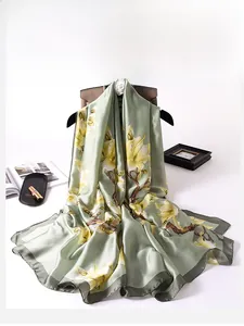 Detail of silk-textured scarf with yellow magnolia print and elegant green satin finish