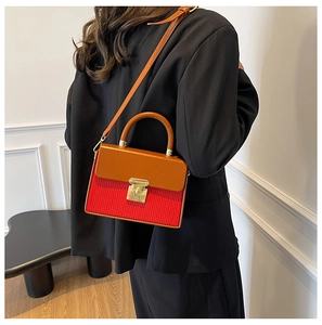 Detail of crossbody box bag with red pleated texture and brown leather strap and gold lock