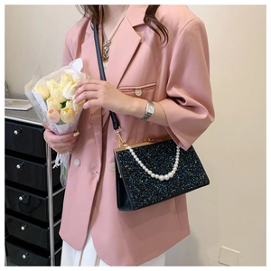 Chic black sequin evening bag with white pearl handle strap shown in a lifestyle setting