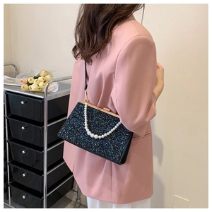 Detail van glitter handtas met parel handvat en gouden sluiting tegen roze blazer
