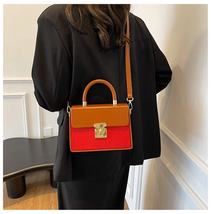 Detail of trendy color-block crossbody bag with red pleated texture and orange handle