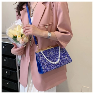 Detail of royal blue sparkly handbag featuring a pearl handle and secure metal clasp