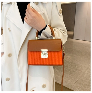 Detailed shot of the two-tone box bag with caramel flap and orange pleated texture