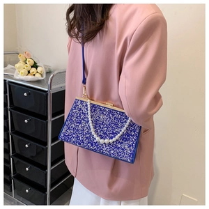 Detail of blue glitter evening bag with pearl handle and gold clasp on pink blazer