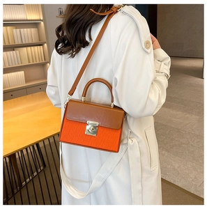 Detail of color-block box bag with orange pleats and gold metal twist lock