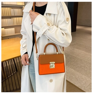 Detail of color-block box bag featuring orange pleated texture and gold push-lock closure