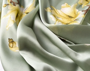 Macro shot of silky sage green satin fabric with yellow magnolia floral print patterns