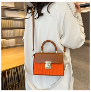 Close-up of contrast color handbag with orange pleats and gold metal twist lock detail