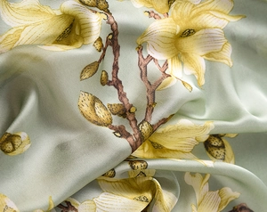 Detailed view of sage green silk scarf featuring realistic yellow magnolia blossoms