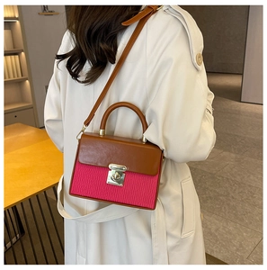Detail of a dual-tone box bag featuring brown leather flap and magenta textured panels