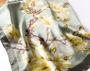 Detail of elegant silk scarf featuring white magnolia floral prints on a sage green fabric
