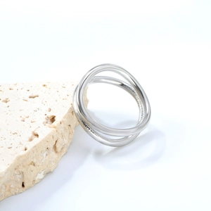 Close-up of polished silver double-layer crossover geometric ring on travertine stone