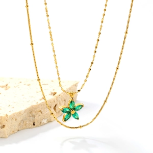 Detailed macro view of a gold flower pendant featuring marquise-cut green zircons on a chain