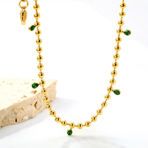 Macro detail of 18K gold bead necklace with water drop emerald green pendant
