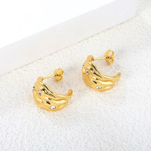 Close-up of golden C-shaped textured earrings with sparkling rhinestones details