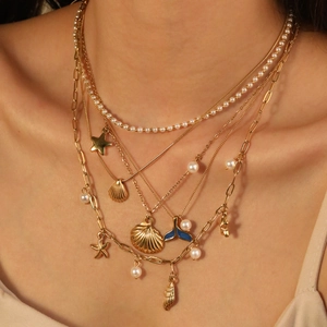 Layered gold necklace with sea shell, starfish and blue enamel fishtail charms